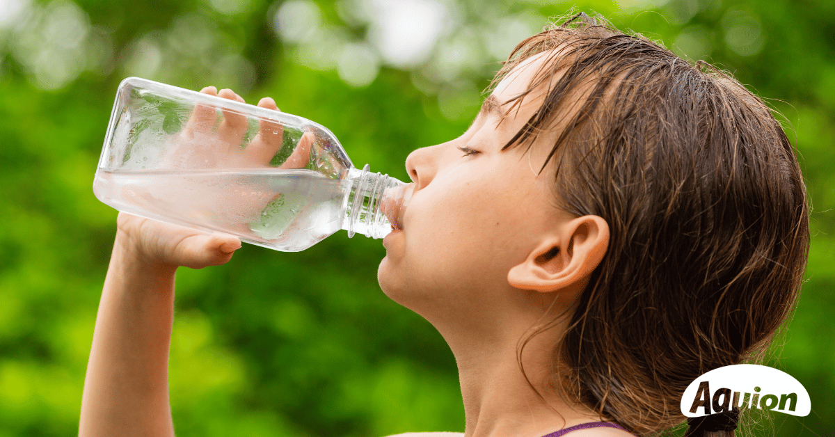 Ein Kind trinkt aus einer Glasflasche Trinkwasser