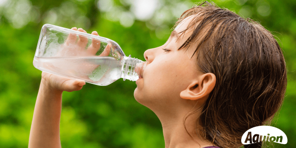 Ein Kind trinkt aus einer Glasflasche Trinkwasser